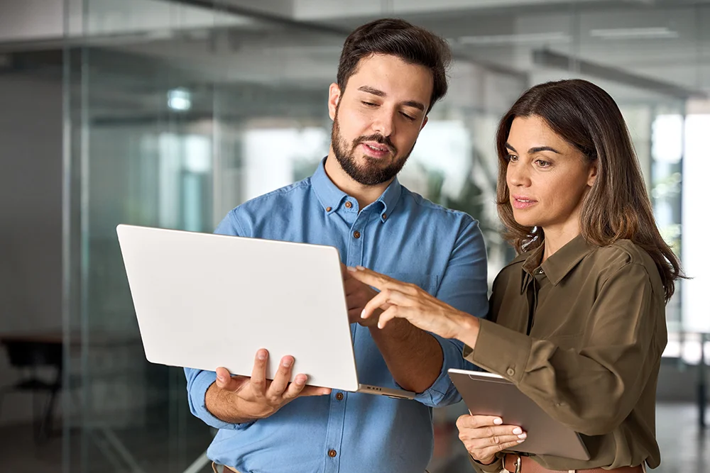 Eine Frau erklärt etwas ihrer Kollegin während einer Besprechung mit Laptop.