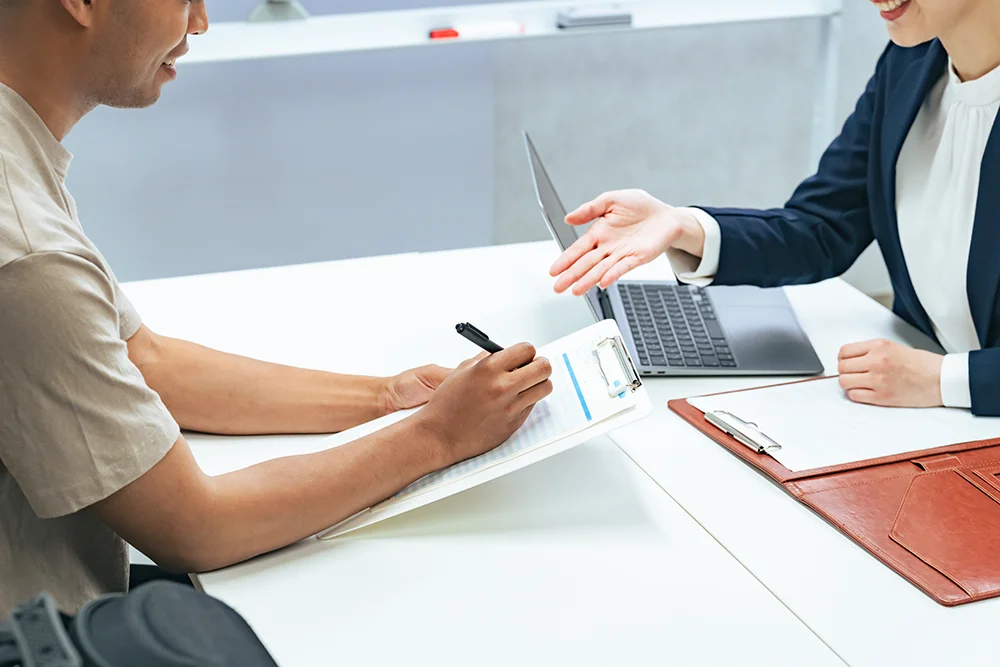 Zwei Frauen unterhalten sich am Arbeitsplatz, eine gestikuliert beim Sprechen.